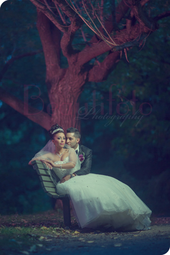 the bride and groom sitting on a bench at a park