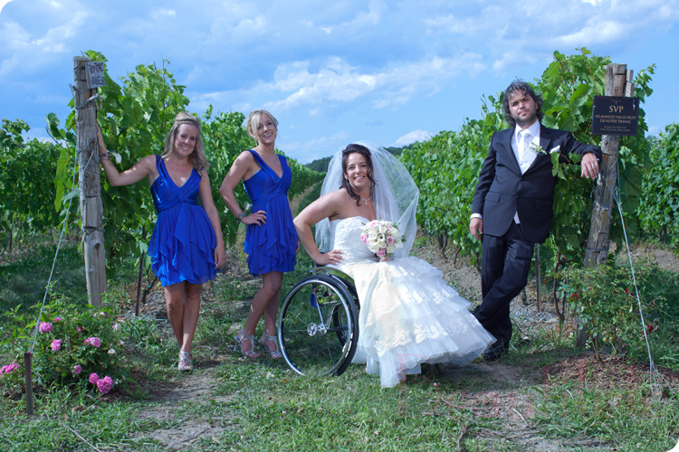 the bride sitting in her wheelchair posing with the groom and her bride's maids